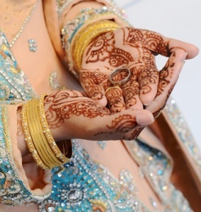 Bridal henna covered hands holding husband's ring
